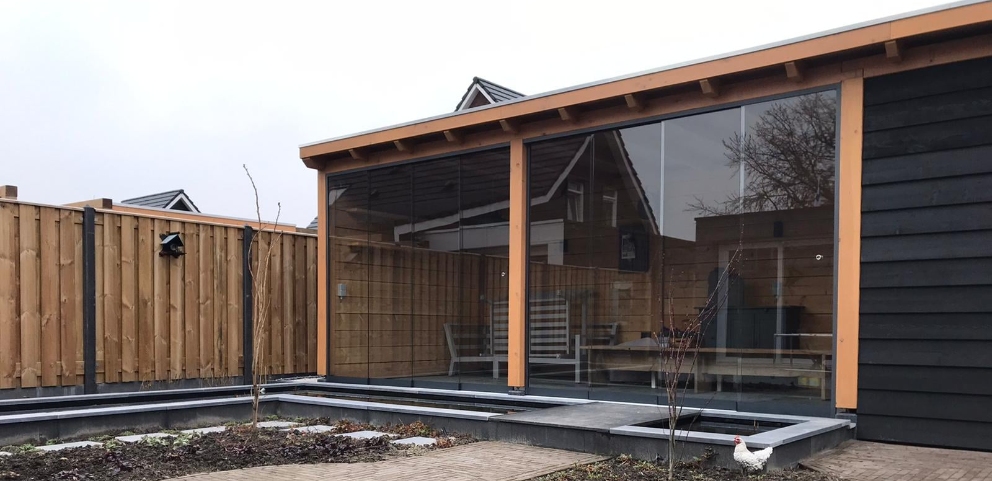 Houten veranda tegen schutting aan met glaswanden